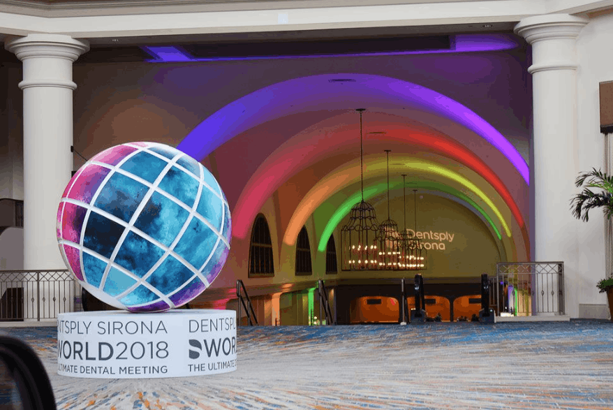 Colorful illuminated archway and globe display creating an immersive entrance for conference attendees.